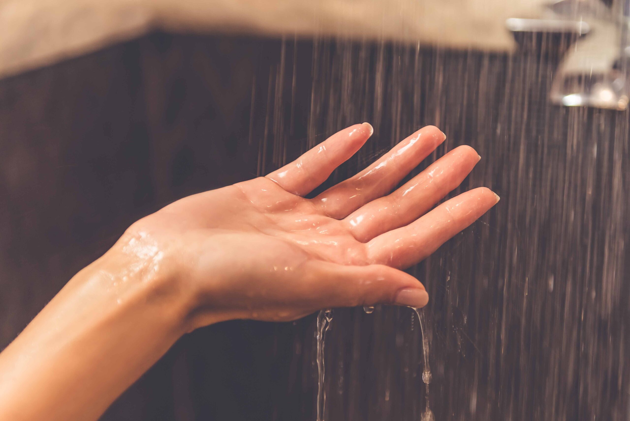 young woman's hand in running shower water